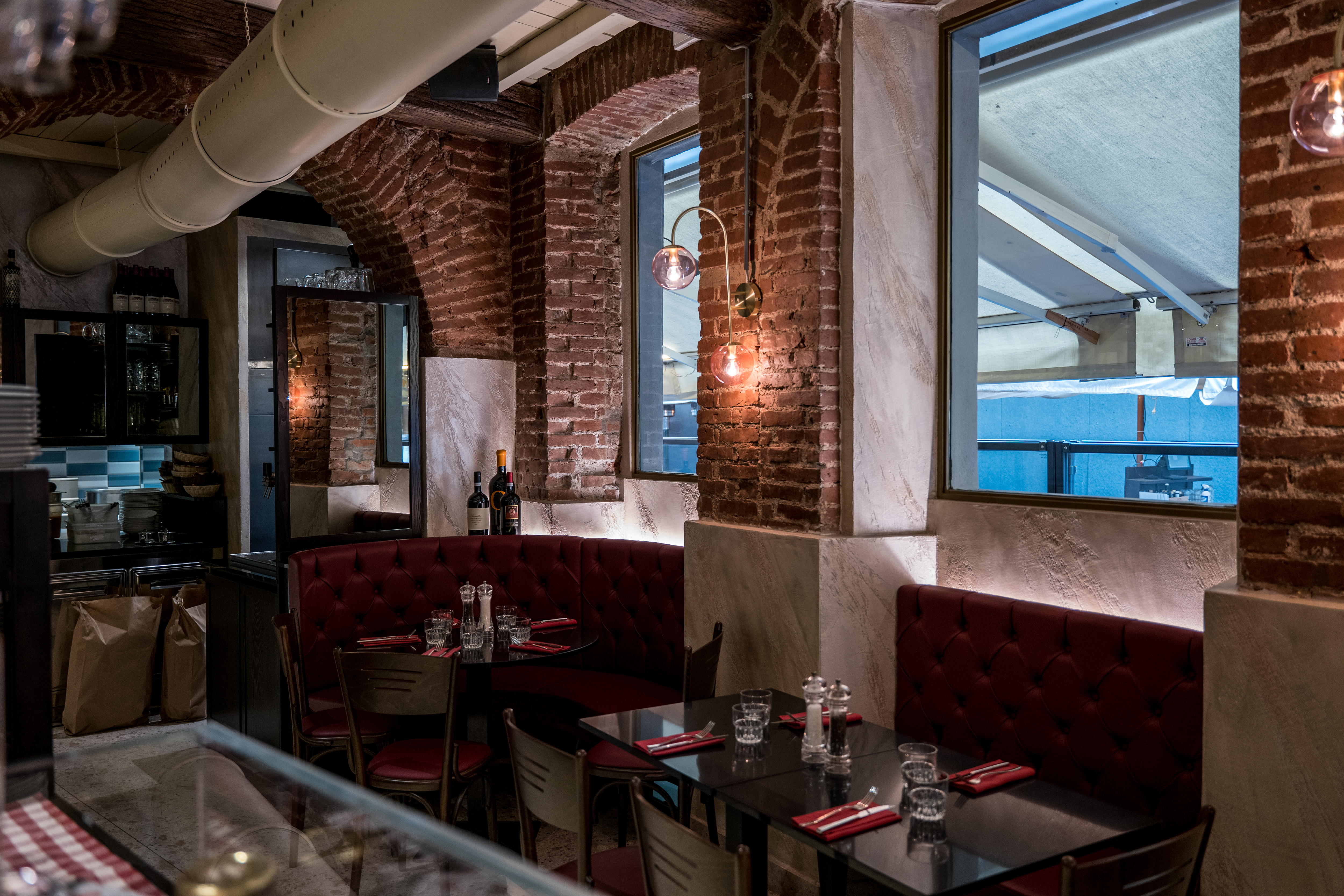 Dettaglio dei tavoli apparecchiati all'interno della Taverna del Borgo Antico, con atmosfera tipica da osteria milanese