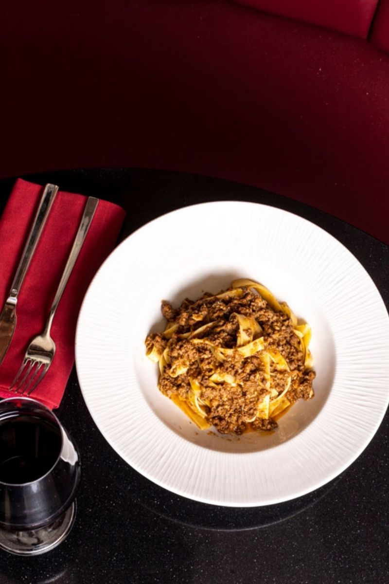 Piatto di tagliatelle al ragù bolognese con calice di vino rosso alla Taverna del Borgo Antico Milano