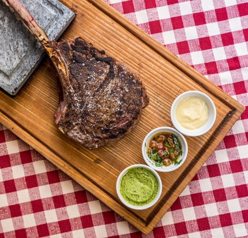 Bistecca Tomahawk alla griglia con salse d'accompagnamento servita alla Taverna del Borgo Antico Milano